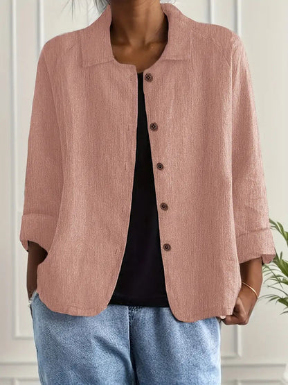 Person wearing a pink corduroy jacket over a black top and blue jeans, standing against a neutral background.