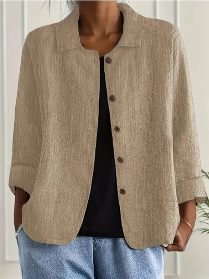 Person wearing a beige button-up shirt over a black top with light blue jeans.
