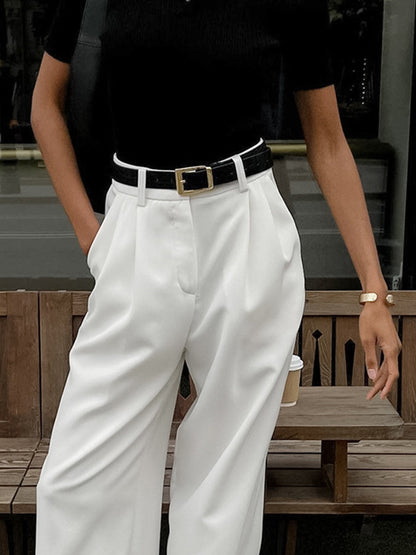 Female model standing in long pants against a plain background.