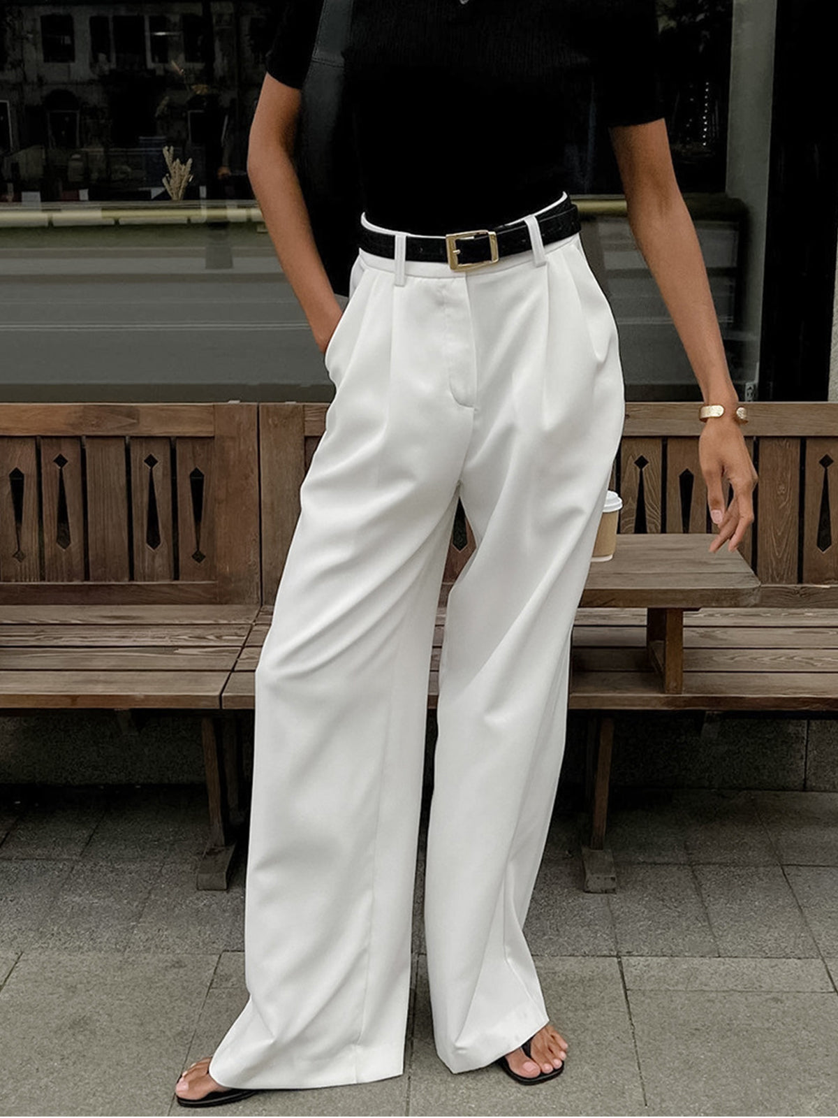 Female model wearing long woven pants on a plain background.