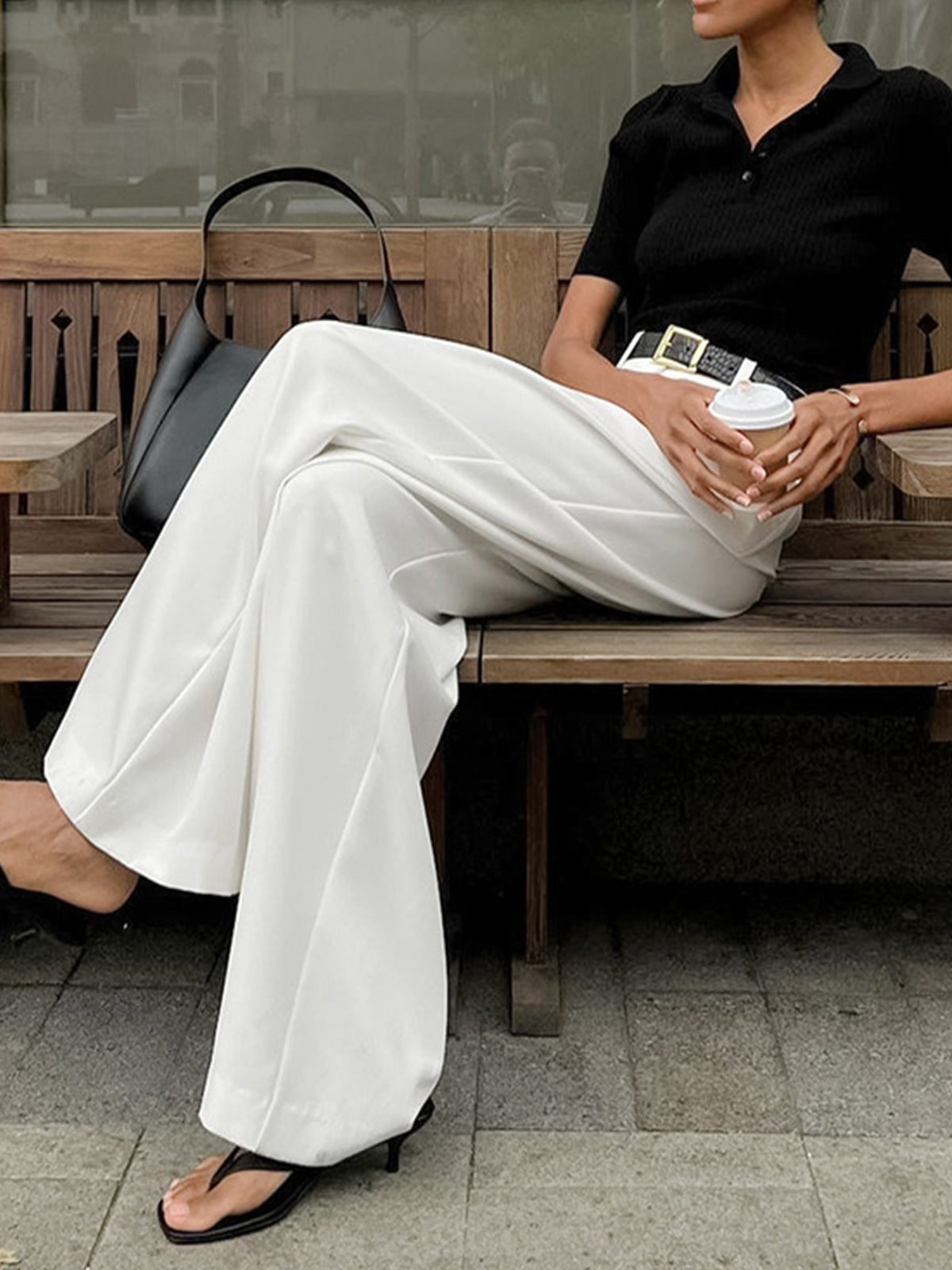 Woman styling regular fit long pants with a simple top on a plain background.