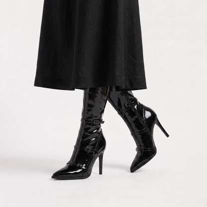 Black knee high boots featuring a sleek patent finish, inner zip closure, and stylish buckled straps, designed with elegant stiletto heels for women. 3
