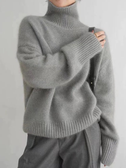 Pull gris en laine à col roulé, manches longues, porté par une personne. Style décontracté et élégant, idéal pour l'hiver. Mode automne-hiver tendance.