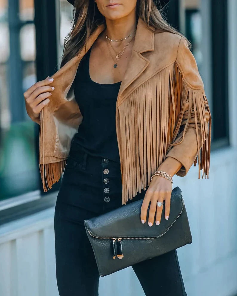 Kameelkleurig suède jasje met franjes, gedragen door vrouw met zwarte clutch | Boutique Moda