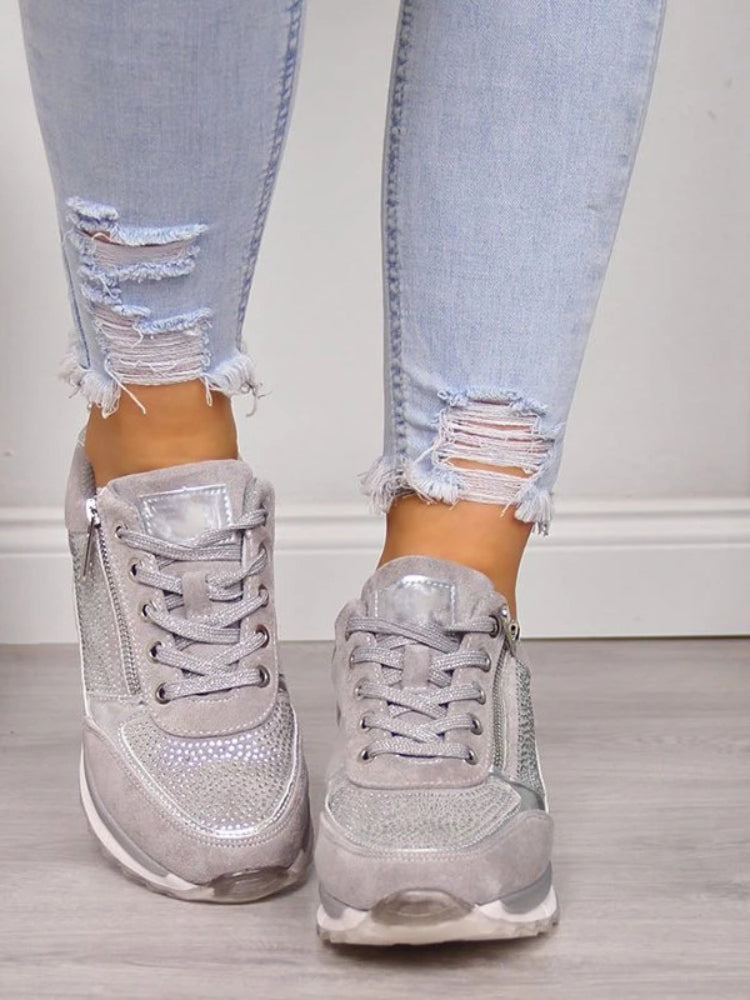 Jeans déchirés et baskets argentées brillantes pour femme sur sol en bois. Mode urbaine, chaussures tendance, style décontracté chic.