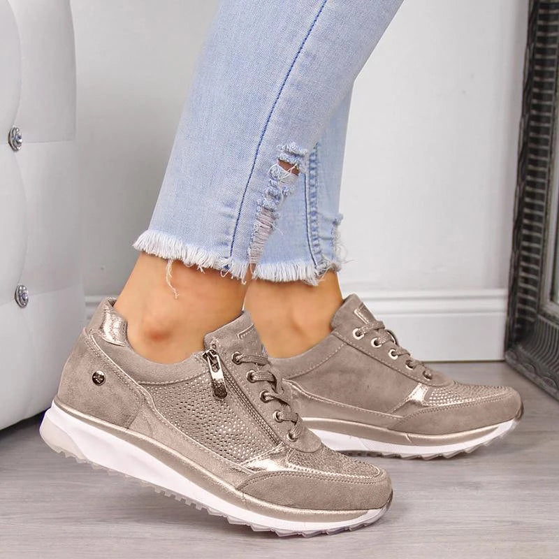 Chaussures de sport beiges pour femme, design moderne avec semelle blanche, portées avec un jean déchiré. Mode féminine, confort, style urbain.