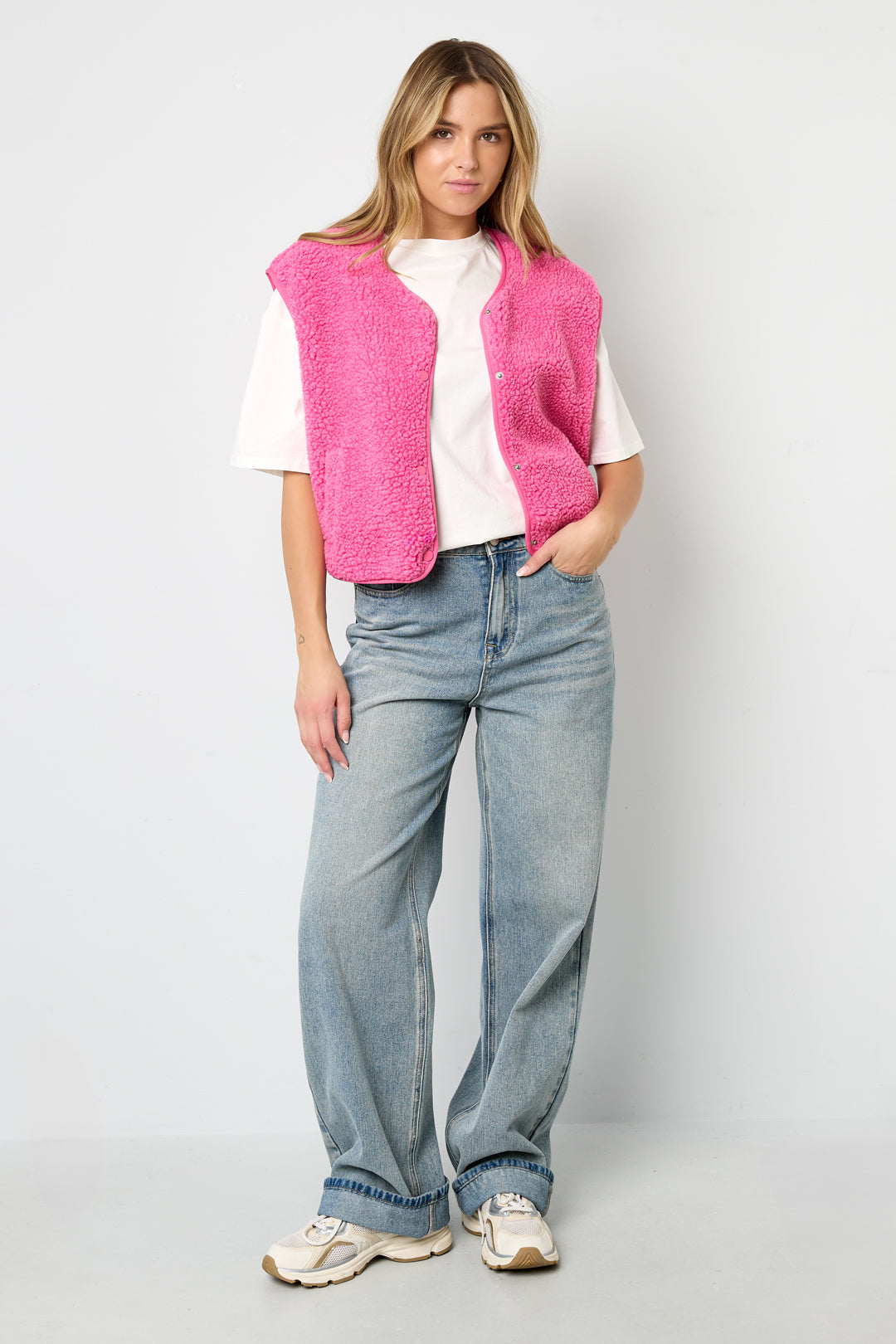 Roze teddyvest mouwloos gedragen door vrouw met witte top en jeans | Boutique Moda