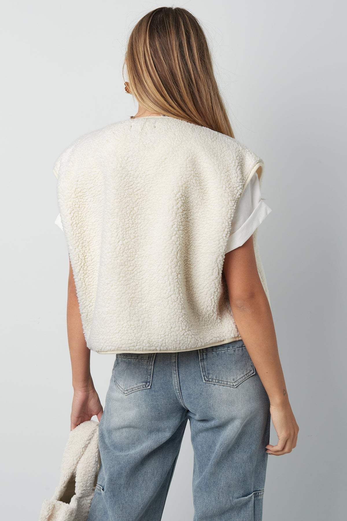 Crème teddyvest mouwloos gedragen door vrouw met spijkerbroek achteraanzicht | Boutique Moda