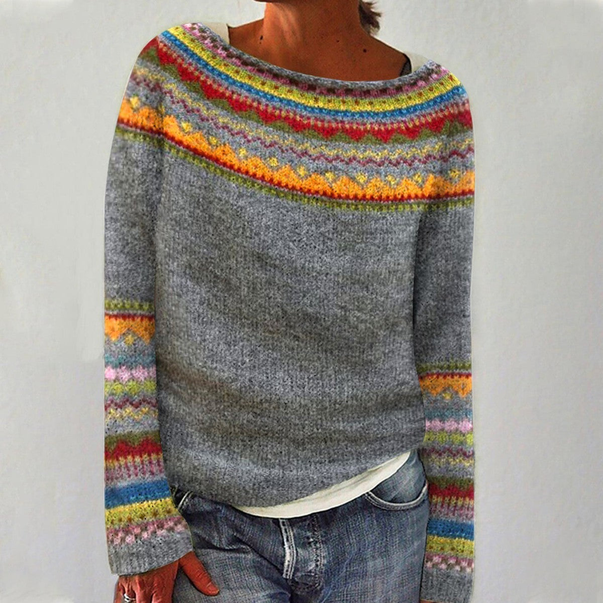 Pull-over en laine gris avec motifs colorés nordiques, col rond, manches longues, porté par une personne. Mode hiver, style scandinave.