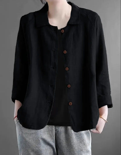 Person wearing a black button-up shirt with a gray background